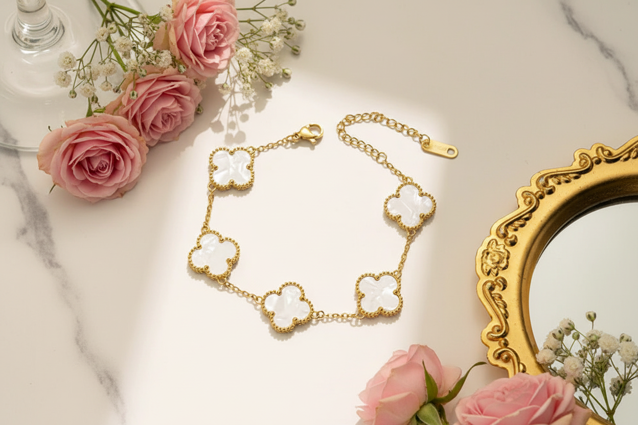 Gold clover bracelet flat lay with flowers